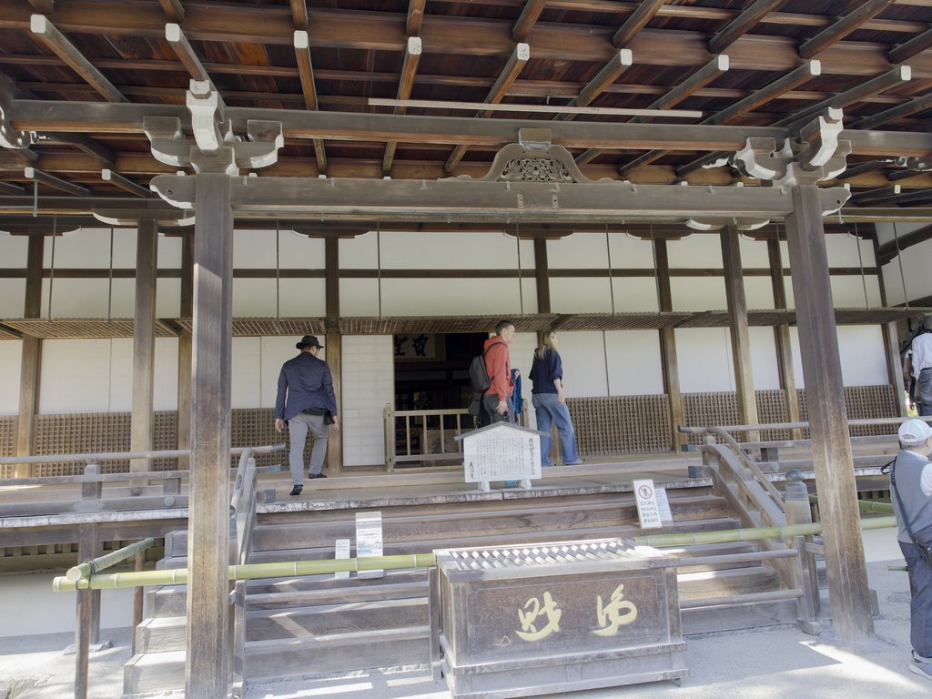 Turyści wchodzą po drewnianych schodach do budynku świątynnego