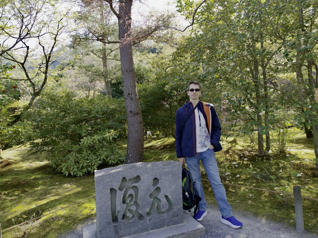 Kamil przy kamiennym monumencie z japońskimi znakami w ogrodzie