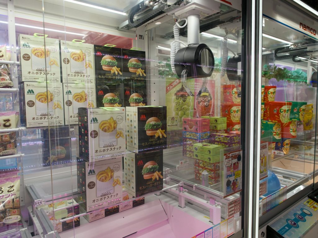 Automat crane game z nagrodami MOS Burger snacks i Namco logo