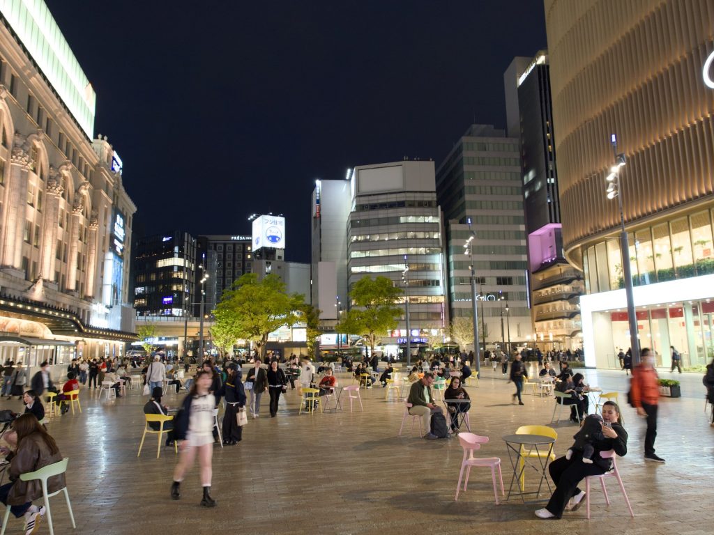 Nocny plac przed stacją Namba z krzesełkami i ludźmi