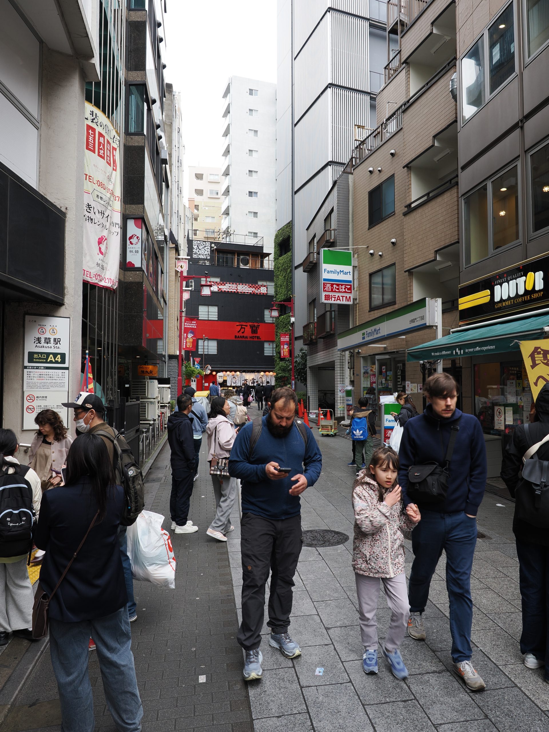 Ulica przy wyjściu ze stacji Asakusa, turyści, hotel Banrai w tle, FamilyMart i Doutor po prawej