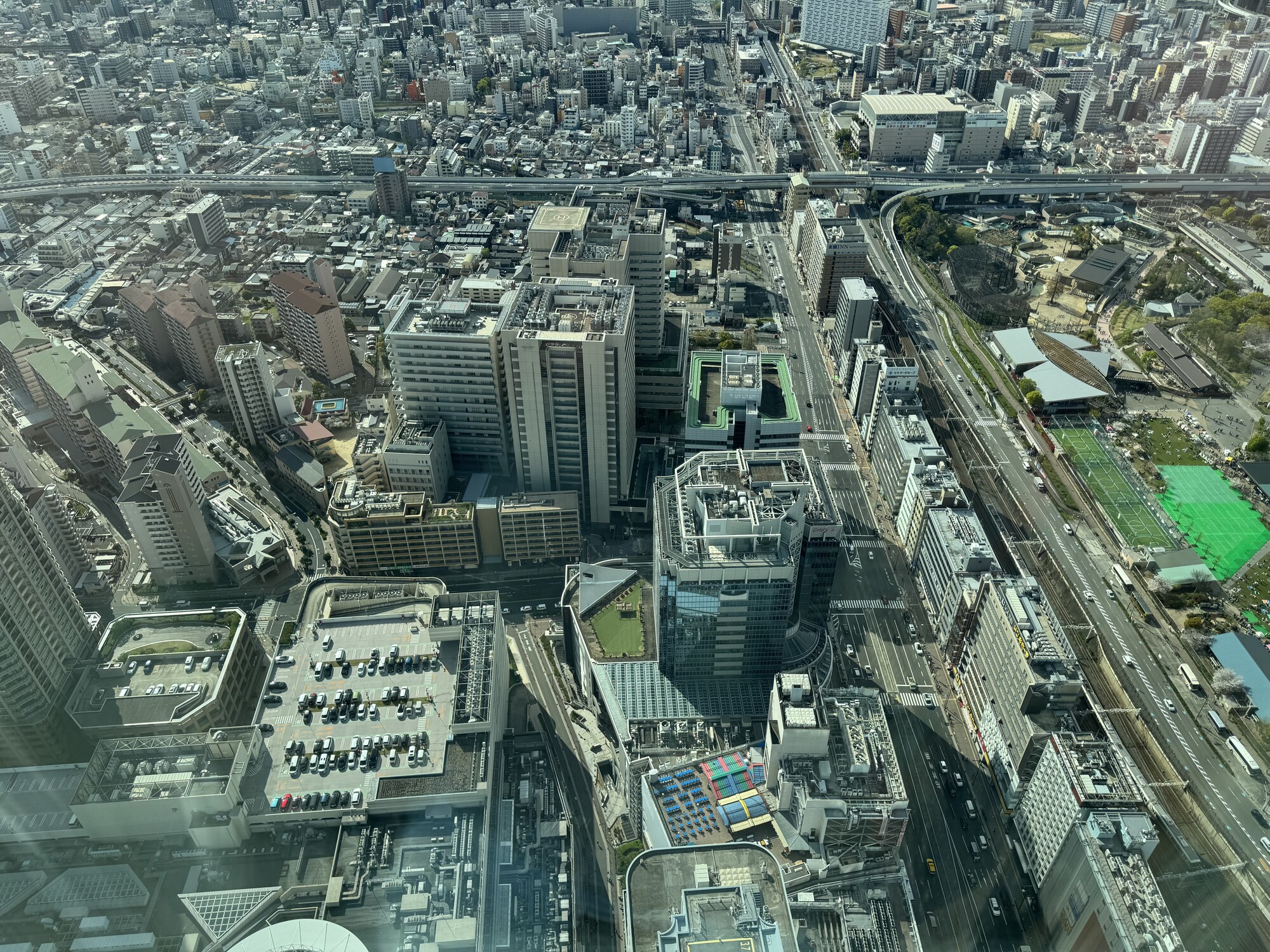 Panorama Osaki z góry — gęsta zabudowa rozciąga się do horyzontu, rzeki i parki między blokami, widok z okna hotelu