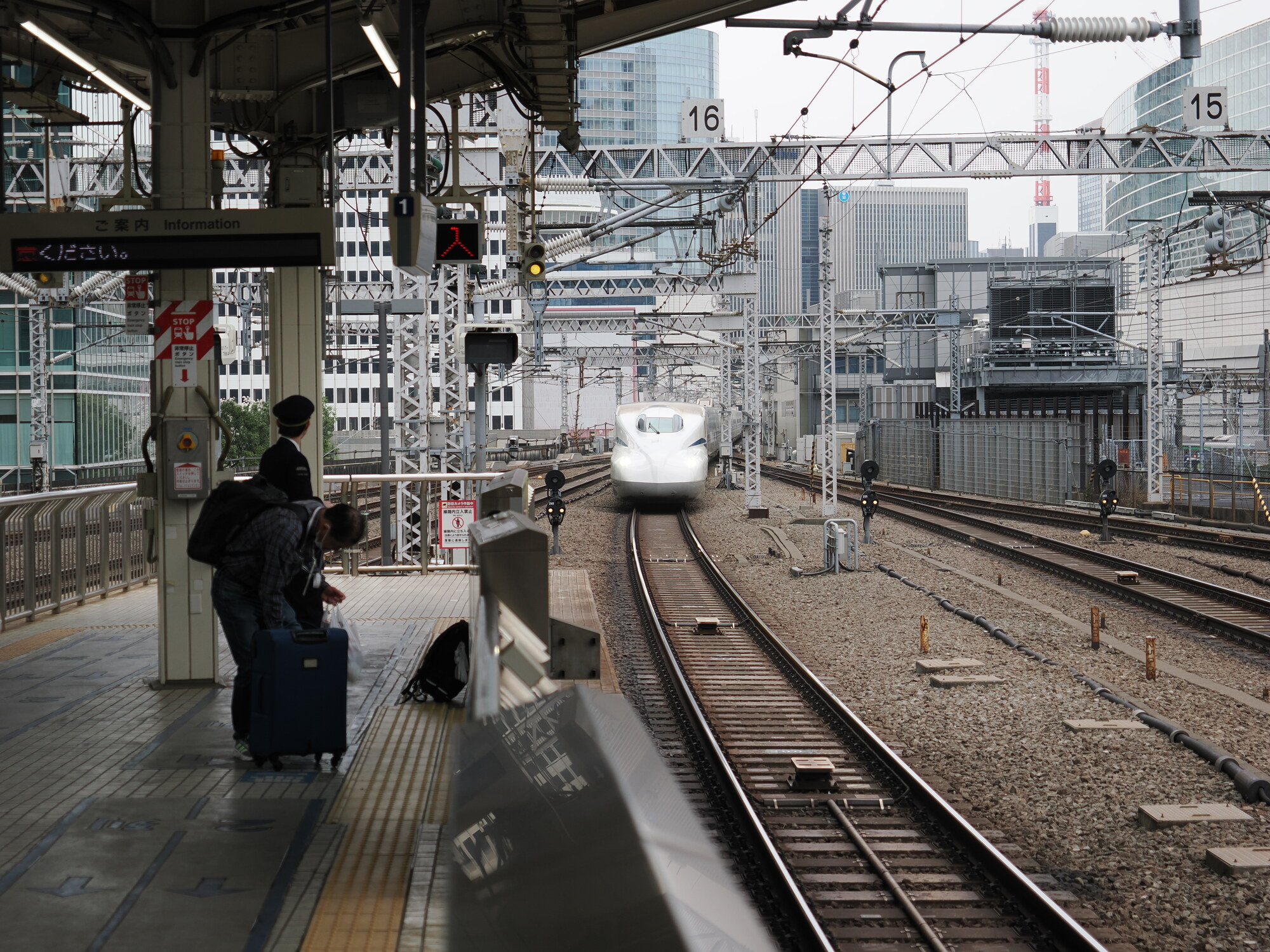 Shinkansen wjeżdżający na peron Tokyo Station — widok z peronu 1 na nadjeżdżający pociąg, pracownik JR w mundurze