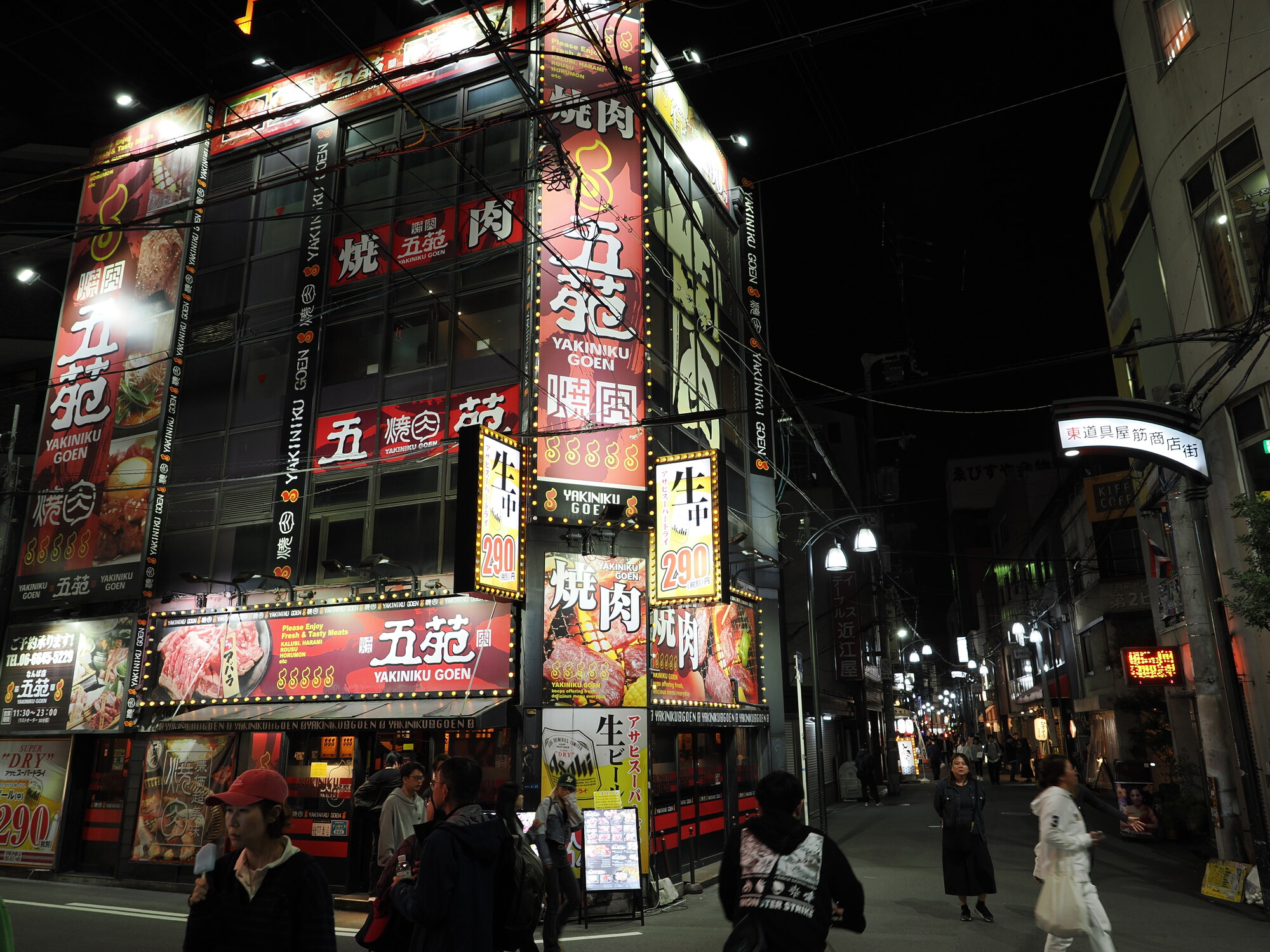 Budynek Yakiniku Goen nocą — czteropiętrowa fasada cała oklejona neonami i szyldami 焼肉五苑, menu z 290 yen, tłum przed wejściem
