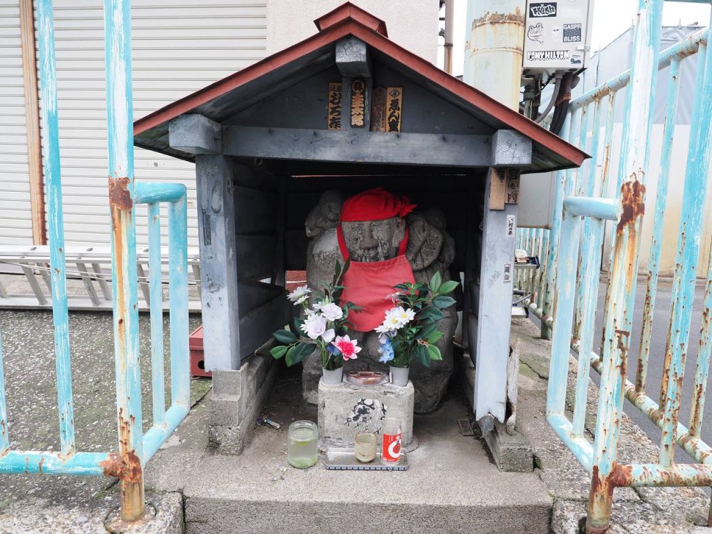 Kamienna figurka Jizō w czerwonym fartuszku przy wejściu na Tsukiji Market
