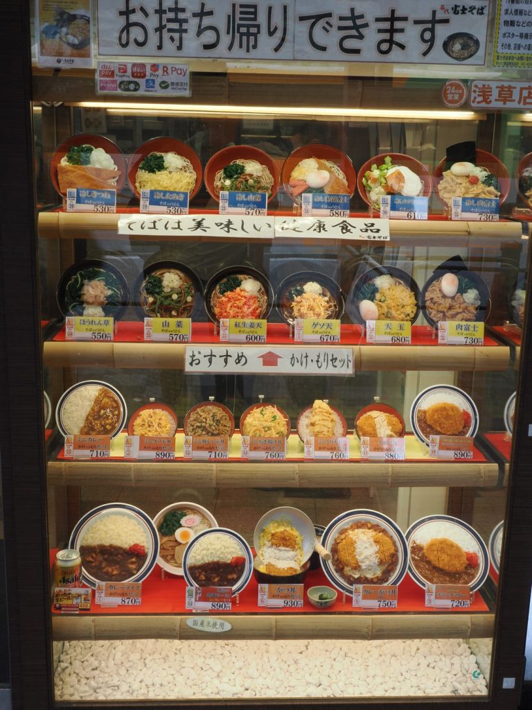 Witryna restauracji Fuji Soba Asakusa — plastikowe modele dań soba, udon, katsudon i zestawy na czterech półkach, ceny od 530 do 930 jenów