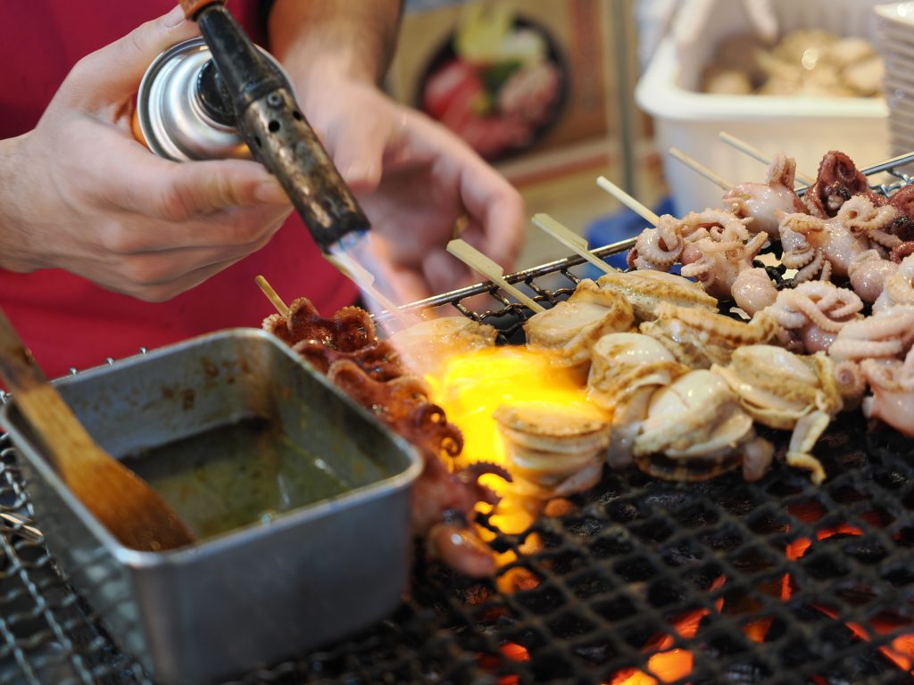 Grill z palnikiem — przegrzebki i ośmiorniczki na węglu drzewnym na Tsukiji