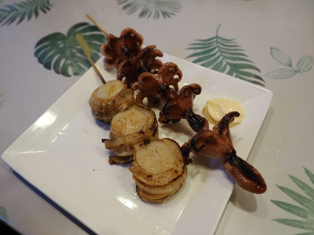 Talerz z grillowanymi przegrzebkami i ośmiorniczkami na szaszłykach