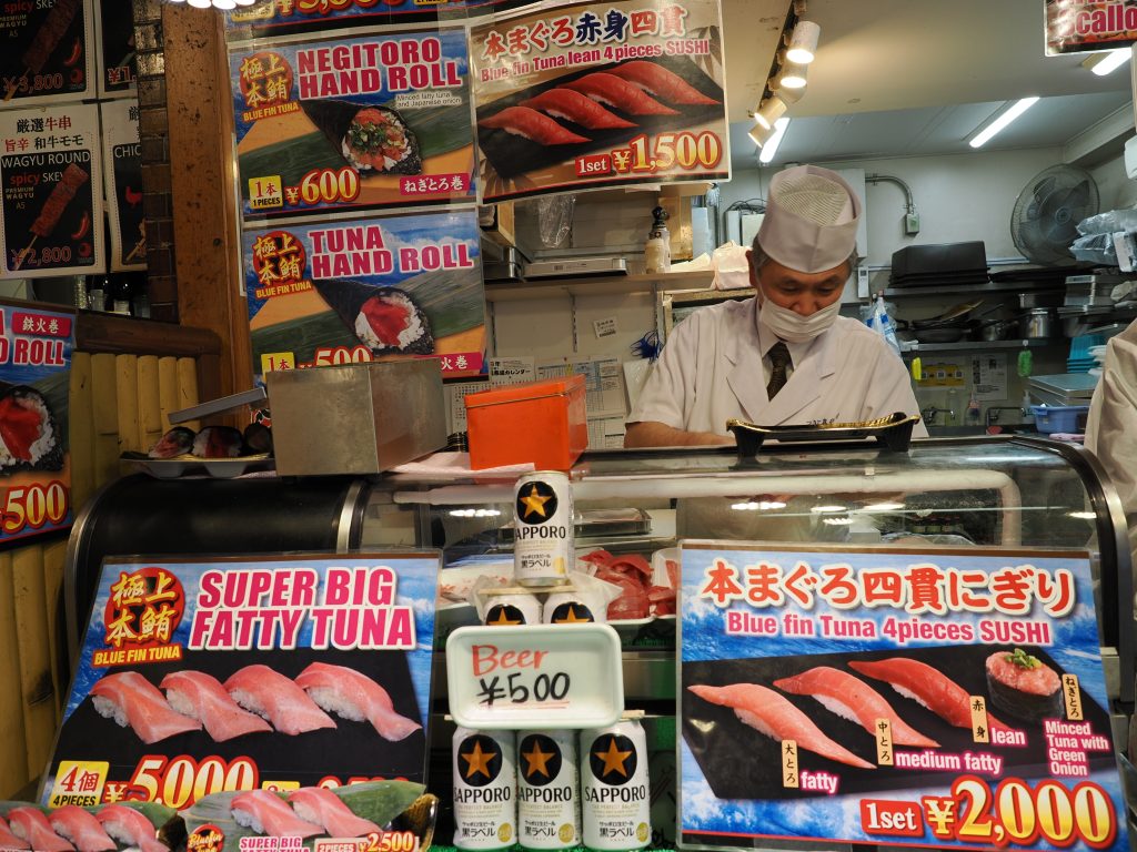 Szef sushi w białym fartuchu, menu z tuńczykiem i Sapporo piwem za 500 jenów